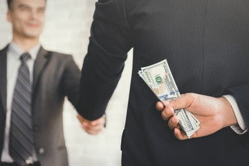 Businessmen making handshake with hidden money at the back