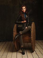 Fototapeta na wymiar Beautiful, self-contained, confident and successful young woman is posing in a stylish black leather jacket (studio shoot of catalogue of fashionable clothes, model demonstrates the collection)