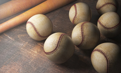 Numerous balls and bats on wooden desk