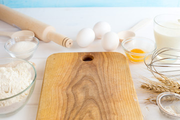 Ingredients for pizza on a wooden background. Flour, whiteboard, eggs on white background