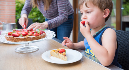 Kid eating a strawberry pie on a outdoor table