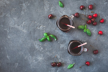 Cherry juice and fresh cherries on black background. Top view, flat lay