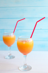A cocktail of orange juice, grenadine and vodka with ice in a glass goblet on a blue background.