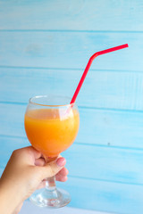 A cocktail of orange juice, grenadine and vodka with ice in a glass goblet on a blue background.