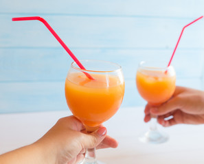 Two cocktails with orange juice and tequila on a blue background. Summer drink with a straw in a glass