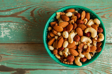 Mixed nuts on a turquoise plate on a turquoise wooden background.