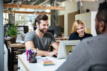 Smiling young colleagues sitting in office coworking.