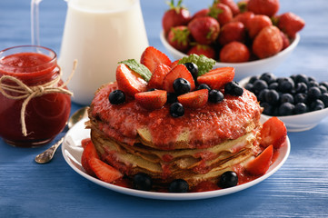 Stack of homemade pancakes with strawberry mousse and berries.