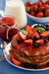 Stack of homemade pancakes with strawberry mousse and berries.
