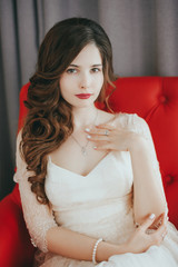 Fototapeta premium Young beautiful bride sitting on armchair and waiting for her groom