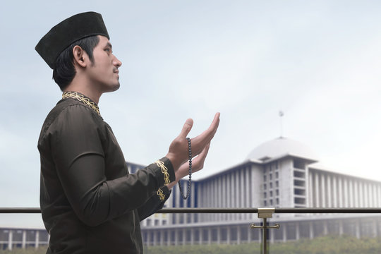 Religious asian muslim man in traidional dress praying to god