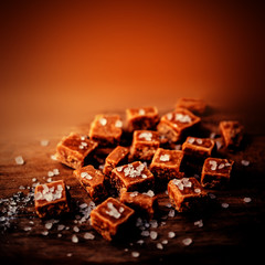 Toffees. Caramel pieces with copy space for your design over dark orange wooden background.