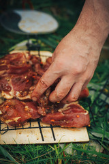 Raw pork steak on ribs. On the grill pan. Male hand puts the meat on the grill