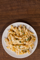 Penne pasta with cream sauce on wooden table with copy space. top view