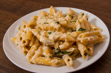 Penne pasta with cream sauce on wooden table