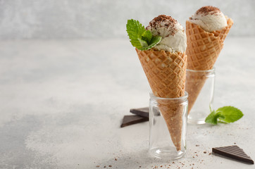 Vanilla ice cream in waffle cone on grey concrete background, selective focus, copy space