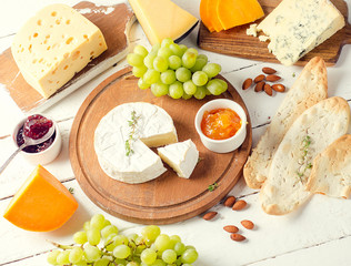 Different kinds of cheeses  with grapes and jam on wooden table