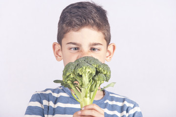 Little boy making a funny face refusing to eat his broccoli