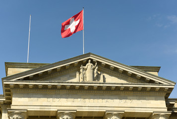 Swiss flag and statue of Justice on Federal Supreme Court of Switzerland. Lausanne, Switzerland