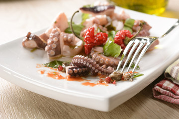 Octopus with seasoning on white dish
