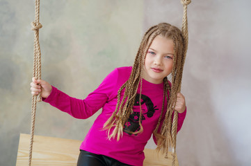 Cute little girl with African braids hairstyle on a swing