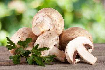 Champignon mushrooms on wooden table with blurred garden background