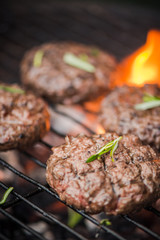 BBq meat burgers over charcoal flames