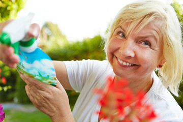 Frau gießt mit Sprühflasche im Garten