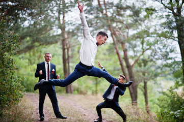Awesome groom and groomsmen getting crazy in the forest and performing tricks on a wedding day.