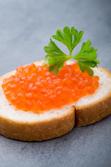 Bread with fresh cream cheese and red caviar on table.