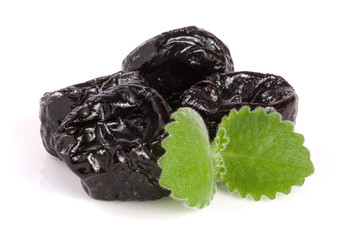 heap of dried plums or prunes with a mint leaf isolated on white background