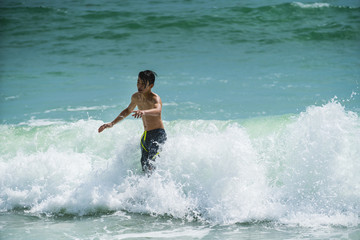 Beautiful young boy playing in the waves