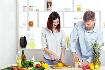 happy couple in love in kitchen making healthy juice from fresh orange