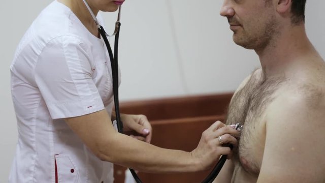 Nurse listens to a male patient via phonendoscope.