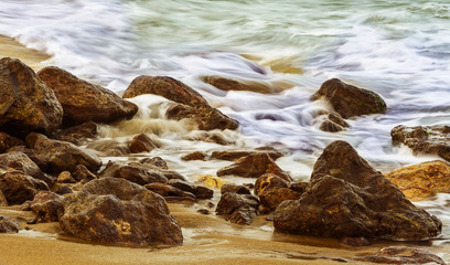 Colorful long exposure of the sea over rocks and sand