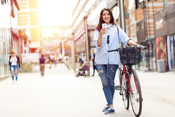 Fototapeta na wymiar Beautiful young woman with bicycle in urban environment.