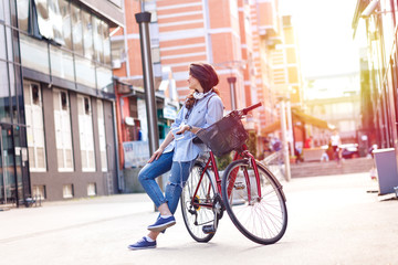 Beautiful young woman with bicycle in urban environment.