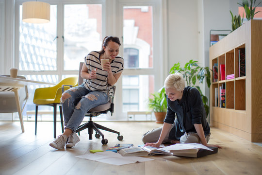 Colleagues discussing ideas with paperwork on office floor