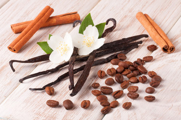 Vanilla sticks and coffee beans with cinnamon on a white wooden background