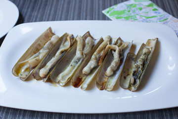 Grilled sea cuttings lie on a snow-white plate that stands on a table on the background of a tourist map