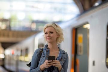 Young adult female on station platform using smartphone