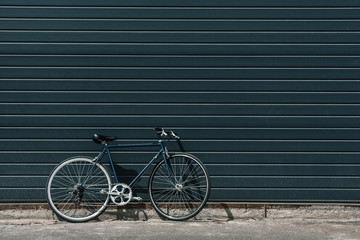Black classic hipster bicycle standing near black wall outdoors