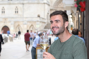 Striking man drinking white wine outdoors