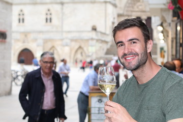 Striking man drinking white wine outdoors