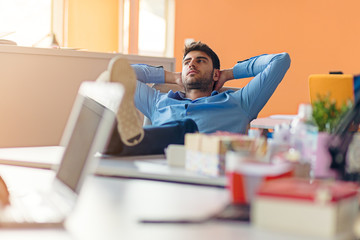 caucasian business person sitting in office thinking daydreaming hands behind head.
