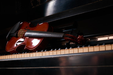 Classical musical stringed instrument violin on piano keys.  Fiddle on piano keyboard.