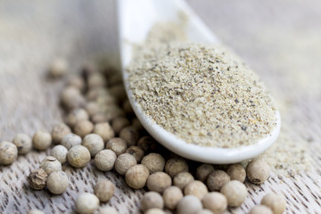 Grain white pepper and white pepper powder on wooden table.