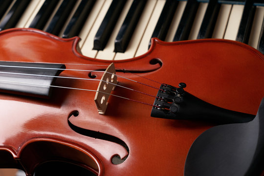 Classical musical stringed instrument violin on piano keys.  Fiddle on piano keyboard.