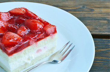 strawberry cake on white dish and wooden background.