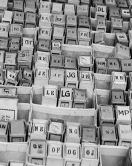 Stack of cardboard boxes with alphabet letters  and syllables. Vintage game at flea market in Paris (France). Black and white.